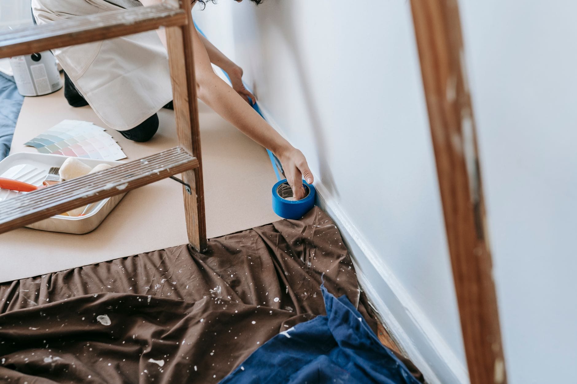 Painter taping trim before painting a room