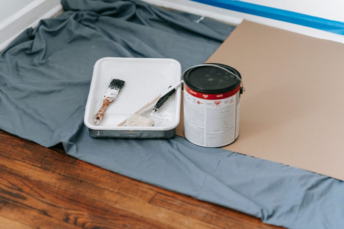 Paint brush, roller and paint can set out on a drop cloth